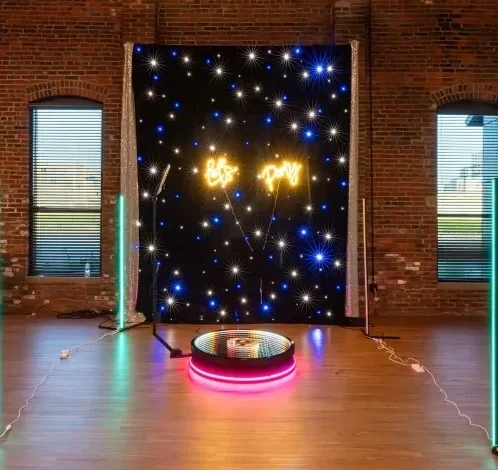 Decorative display with a starry backdrop, neon sign reading 'Let's party,' disco mirror ball on the floor, and colorful light strips on the sides inside a brick-walled room.