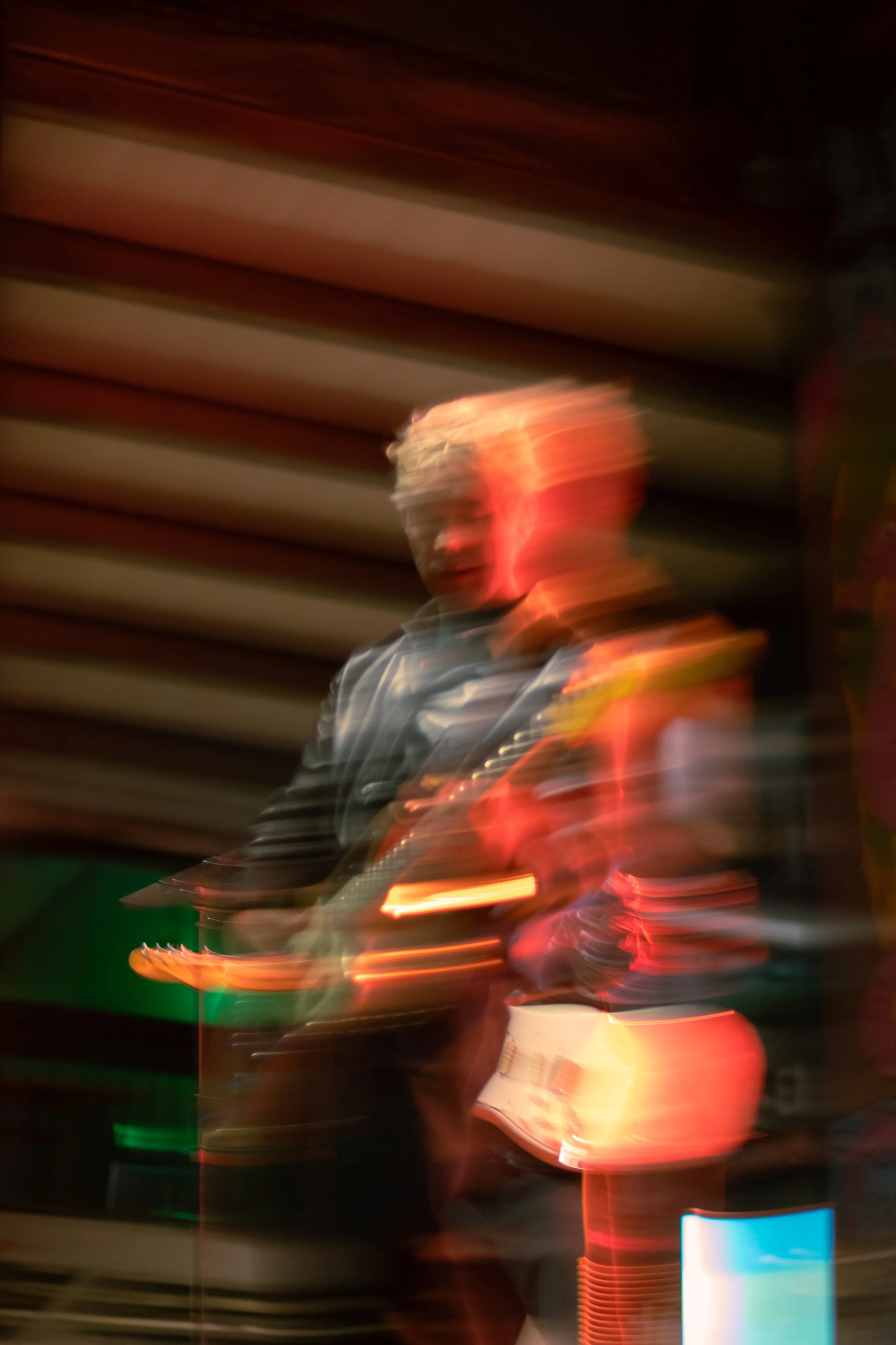 Blurry photo of two musicians playing guitars on stage with colorful lights.