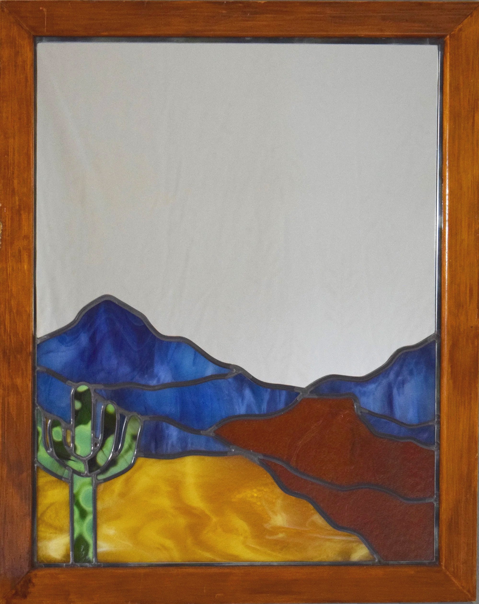 Stained glass window depicting blue mountains, yellow desert, and green cactus.