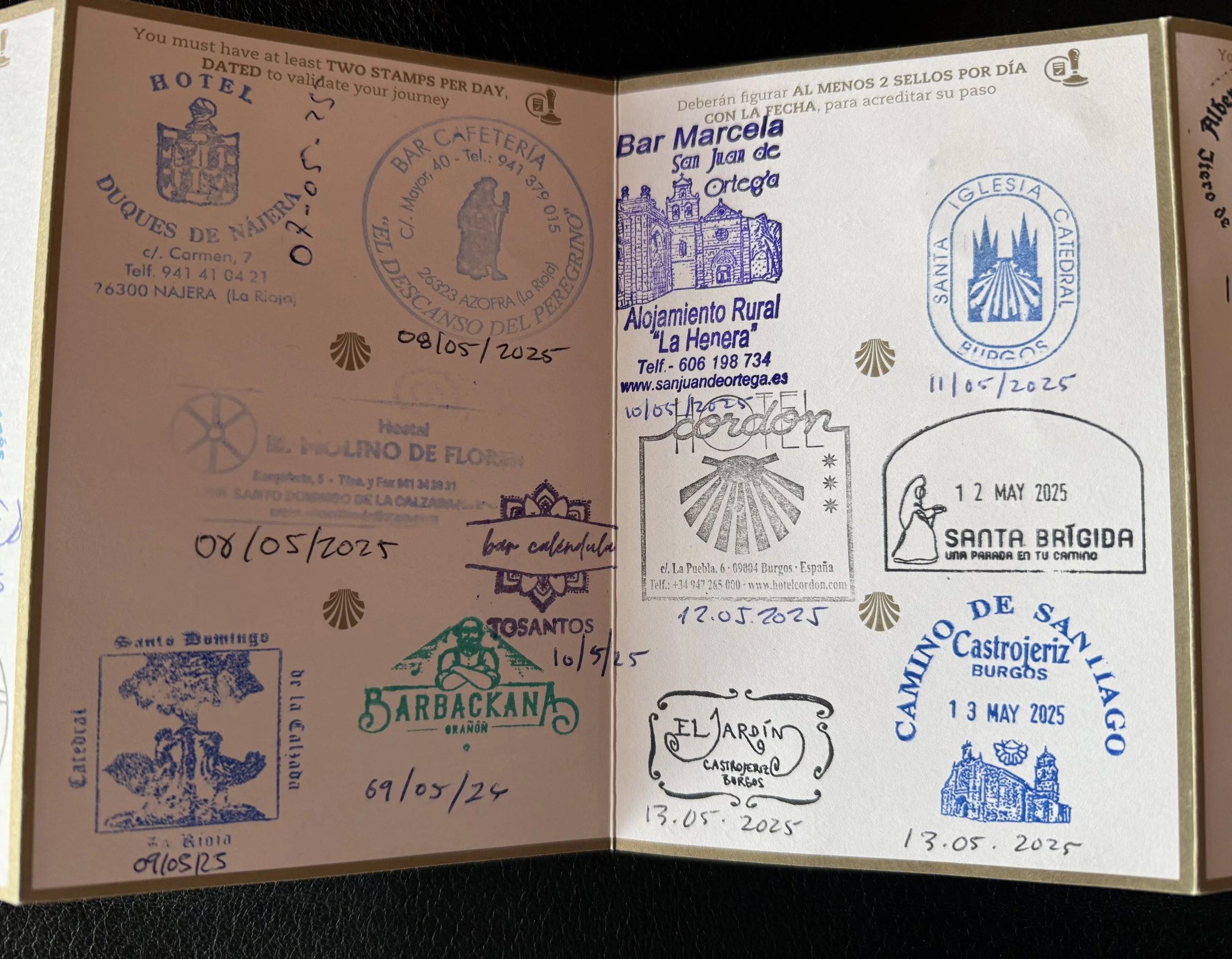 Passport page filled with various blue and black ink stamps from different locations and dates in Spain, including hotel, church, and tourist sites, with handwritten dates.
