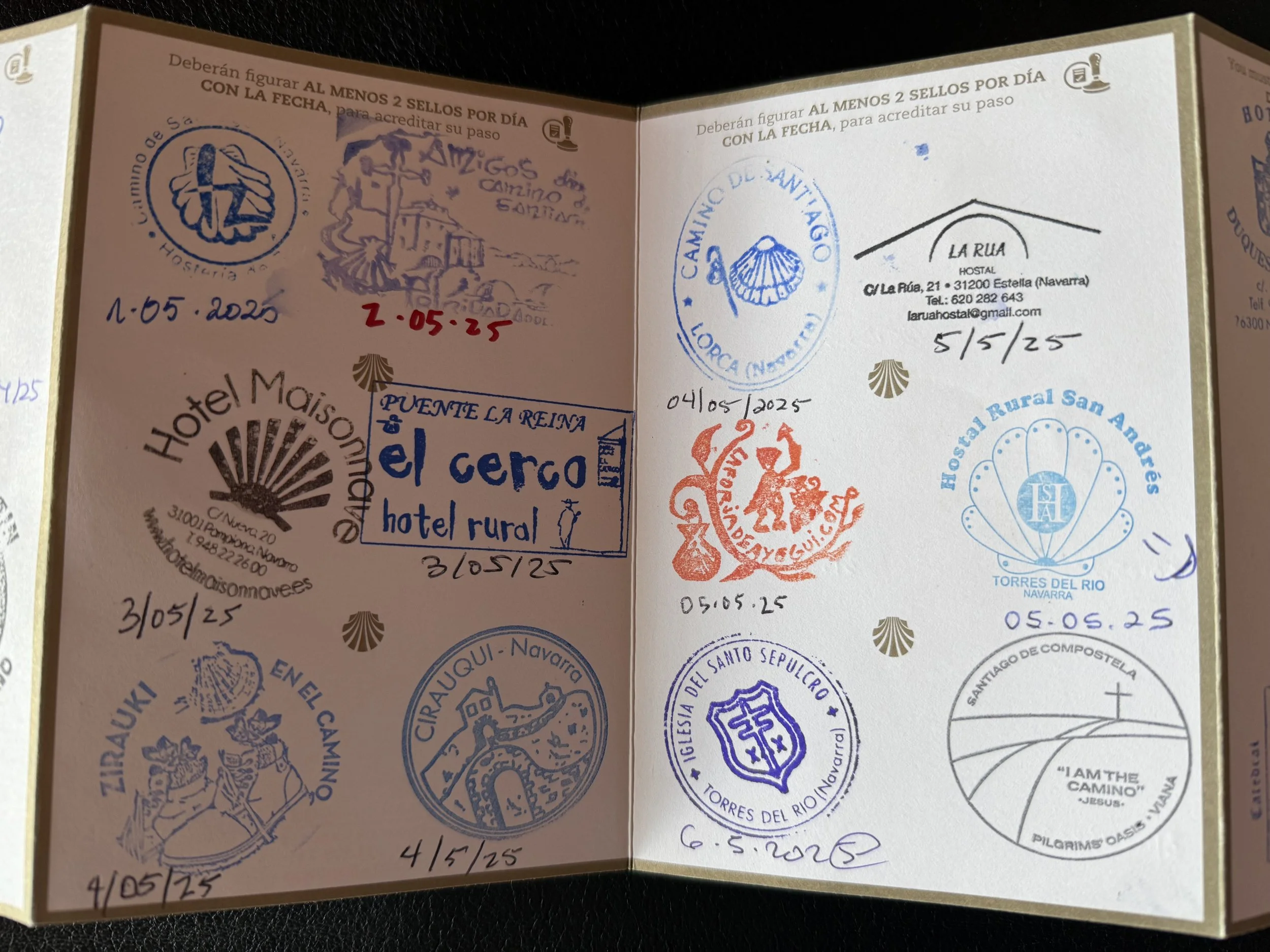 Open passport page with various stamps from different locations in Spain, including dates from 2025, featuring designs of seals, logos, and hand-drawn sketches related to travel and tourism.