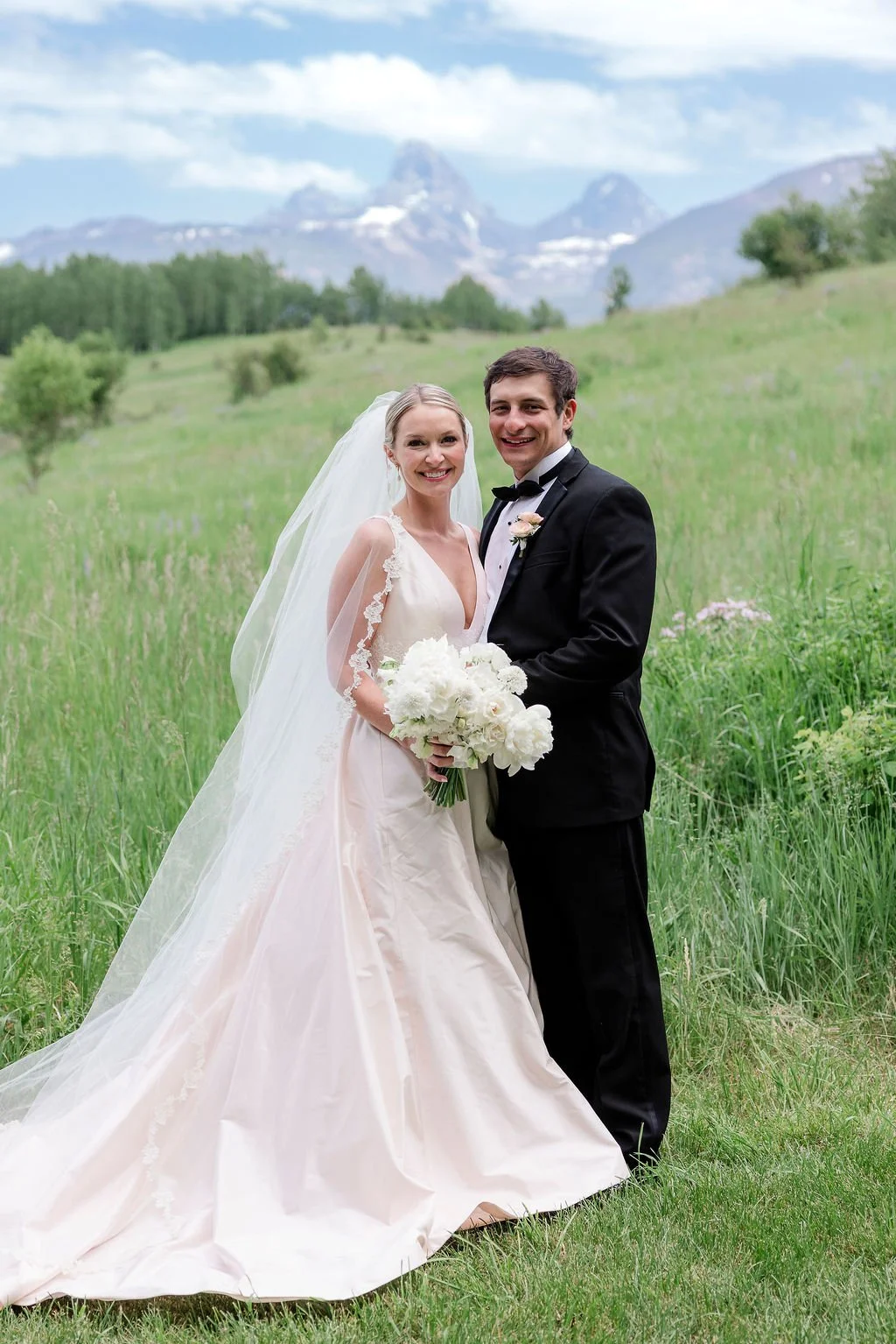 Bride and groom posing in front of the Grand Tetons on their wedding day.