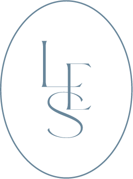 A black oval background with the white or light blue initials 'L', 'E', and 'S' vertically arranged in the center.