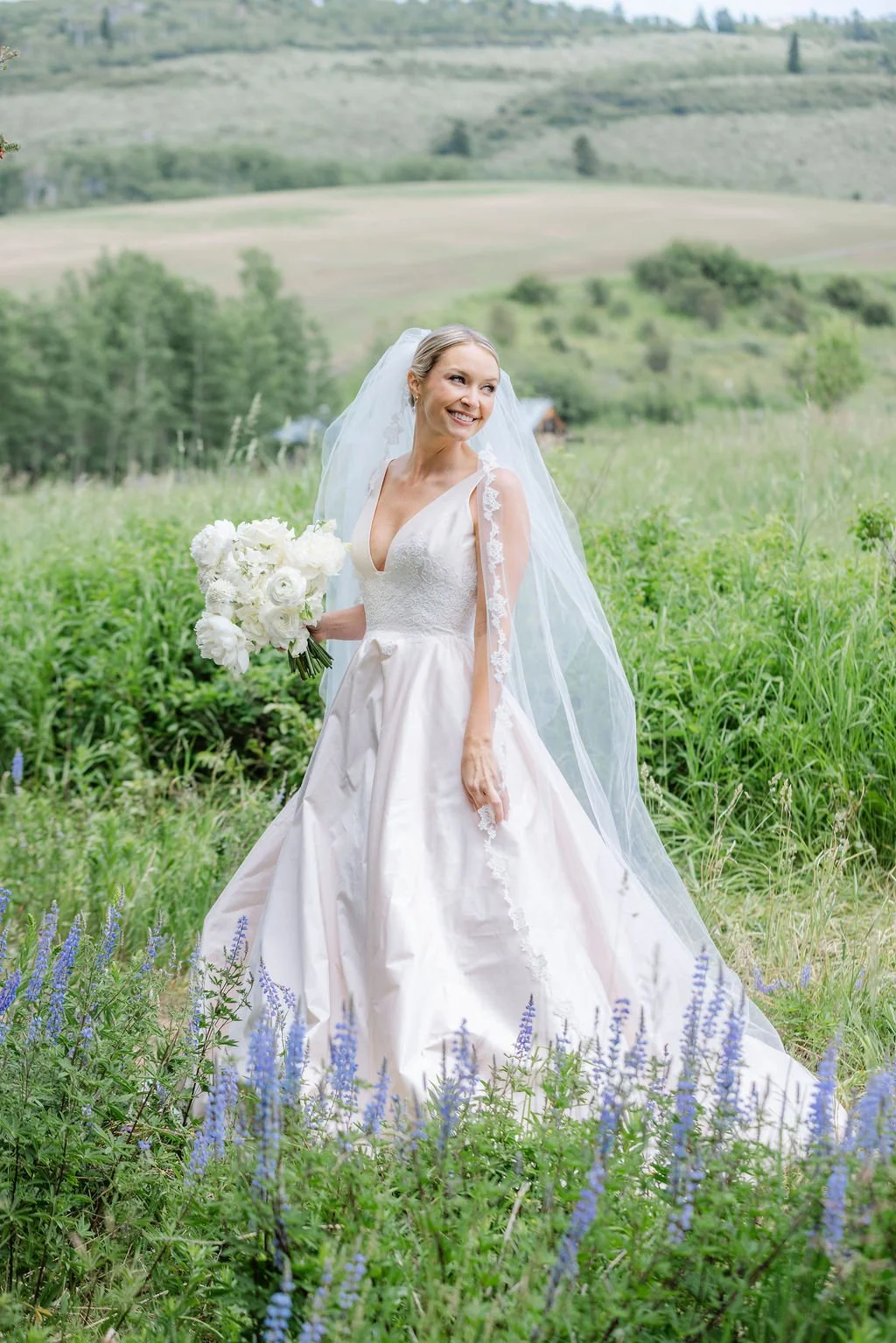 Bride holding white bouquet in a wildflower field during her Grand Teton wedding.