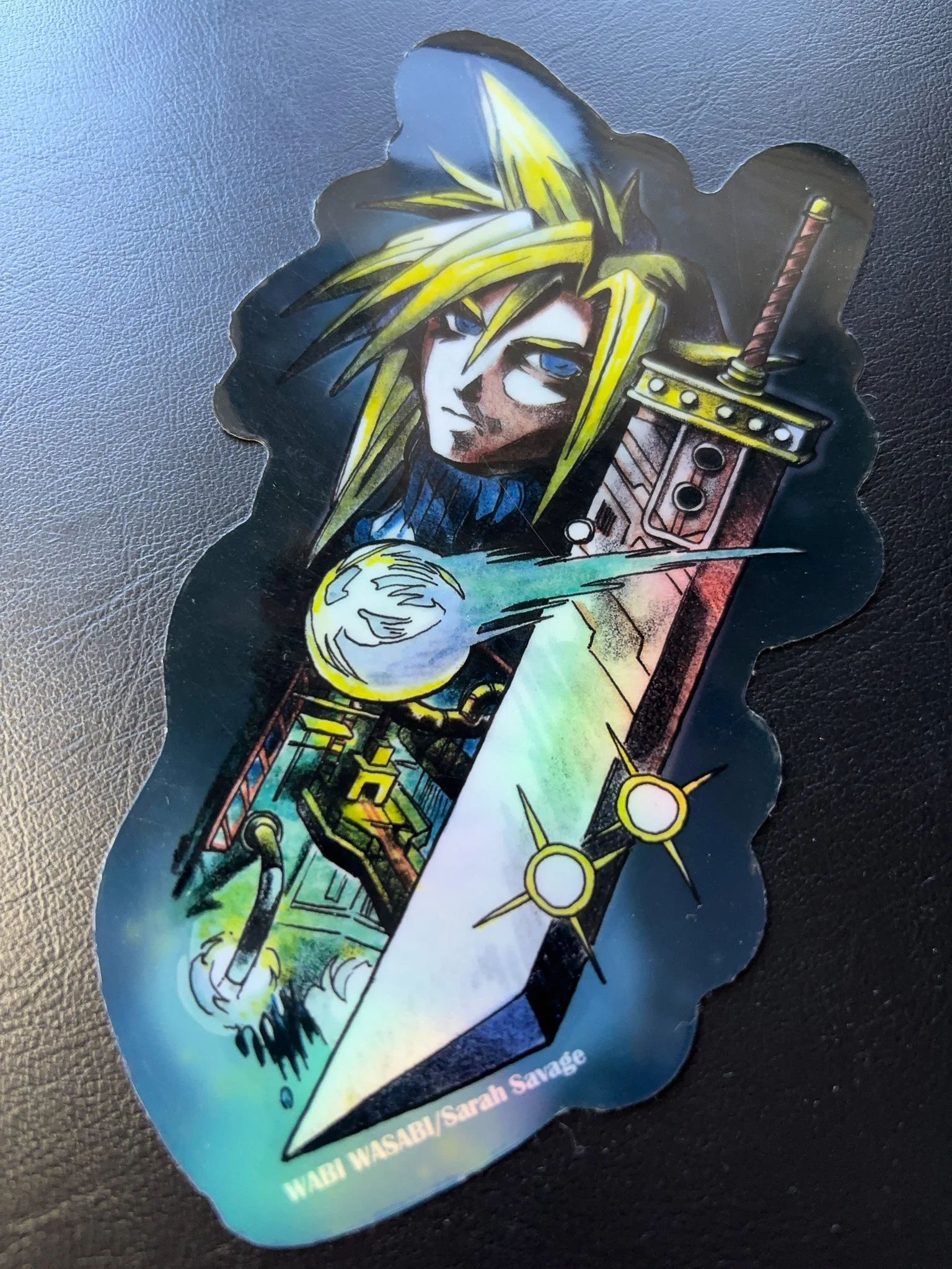 A colorful sticker featuring a stylized illustration of a character with spiky yellow hair, holding a large sword, with a glowing orb and various abstract elements in the background.