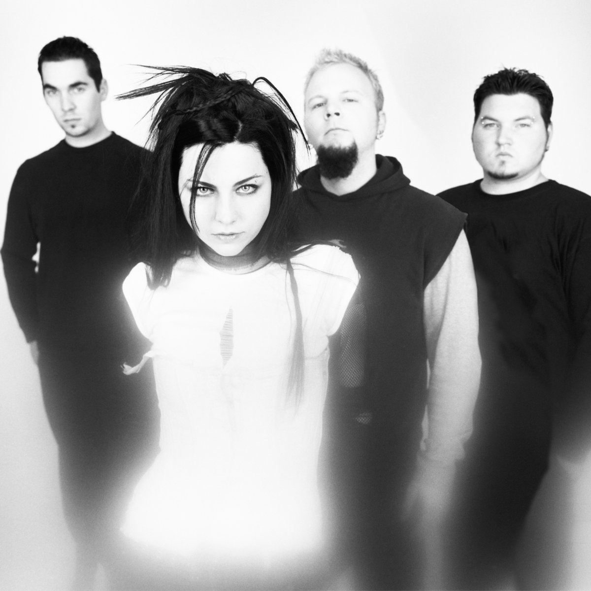 Black and white photo of four band members, with woman front and center, all with serious expressions.