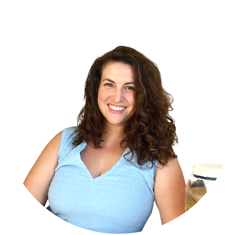 A woman with curly brown hair smiling, wearing a light blue sleeveless top.