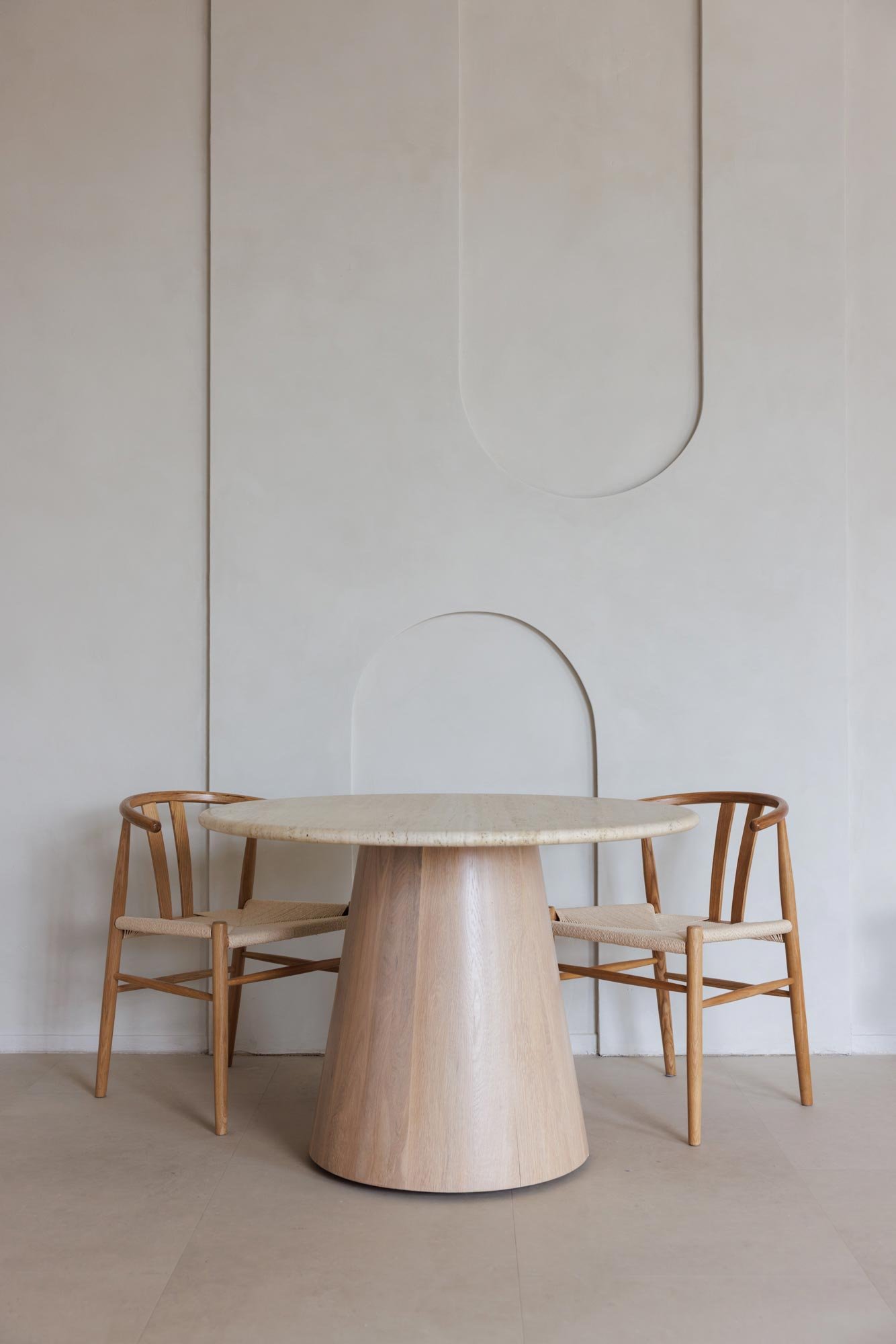 Ein runder Tisch mit zwei Stühlen in einem minimalistischen, weißen Raum.