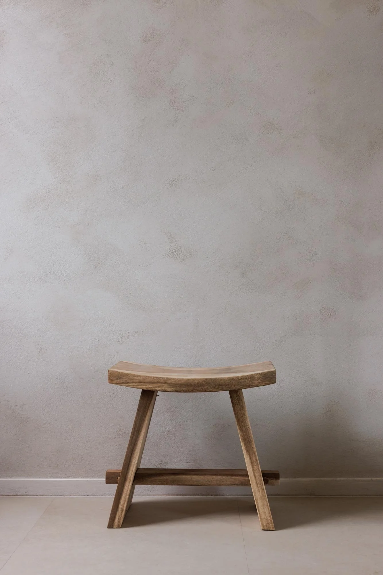 Ein Holzschemel vor einem neutralen Hintergrund.