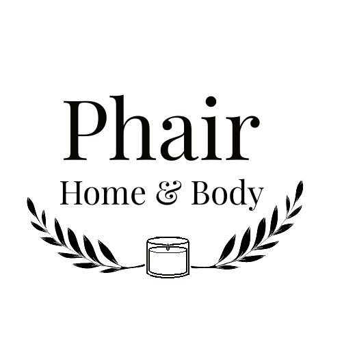 A black circular logo with the words 'Phair Home & Body' and decorative olive branches surrounding a small candle in the center.