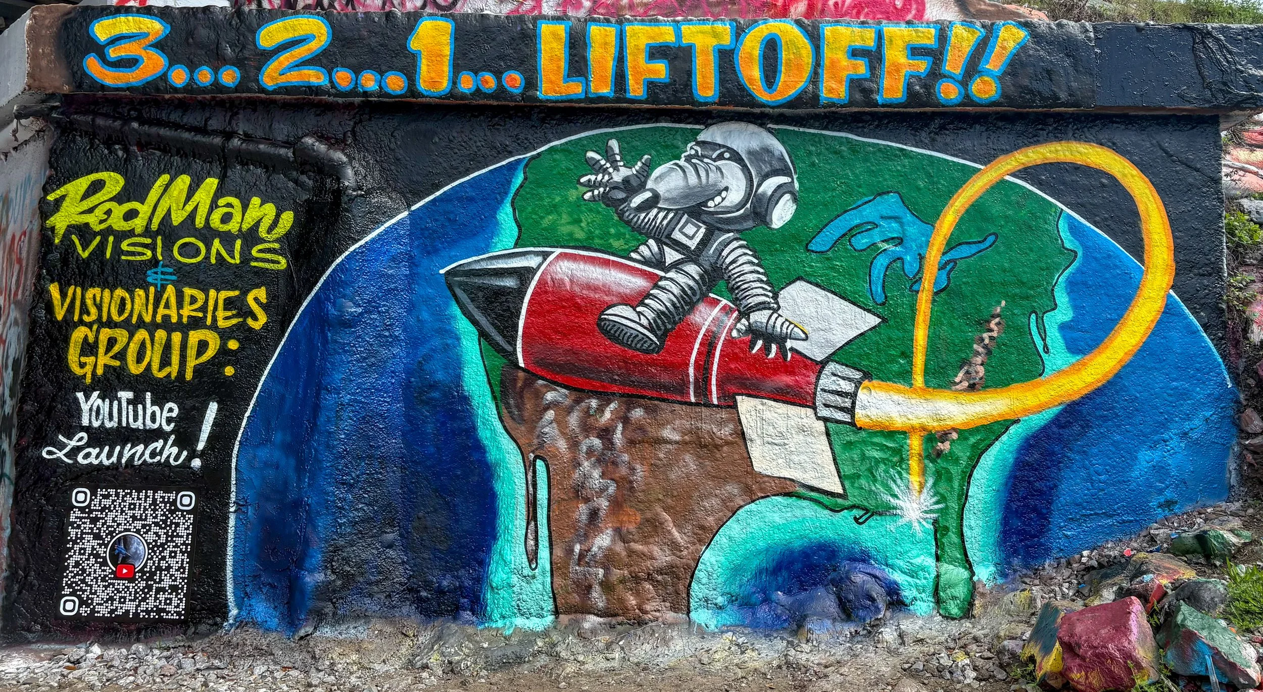 Colorful mural of an astronaut rocket launching from Earth with a stylized face in the sky, with the words '3...2...1...LIFTOFF!!' at the top and information about a YouTube launch event on the side.