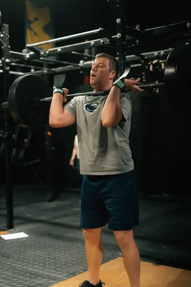 A man lifting a barbell in a gym.