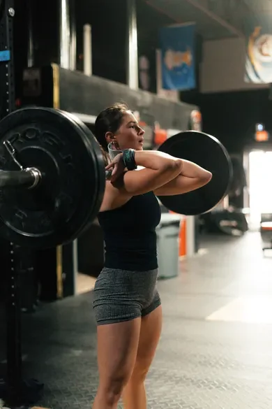 A woman lifting a barbell in a gym.