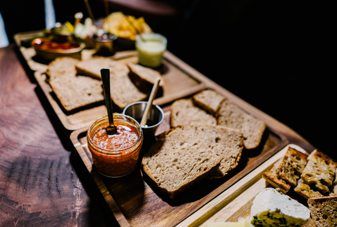 Assorted bread slices, jams, and cheeses on wooden trays for a breakfast or brunch. Spanish tapas. Spanish food boards. Spanish tablas.