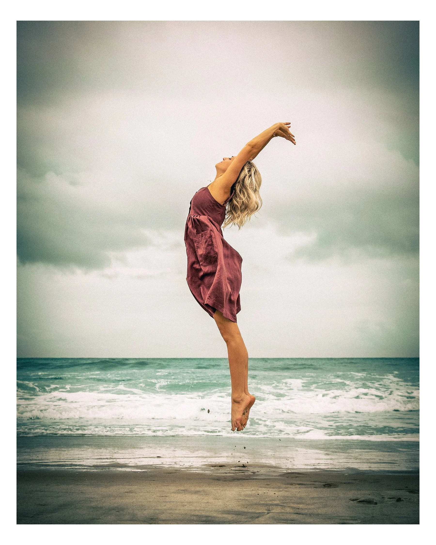 woman jumping on the beach in front of the ocean
