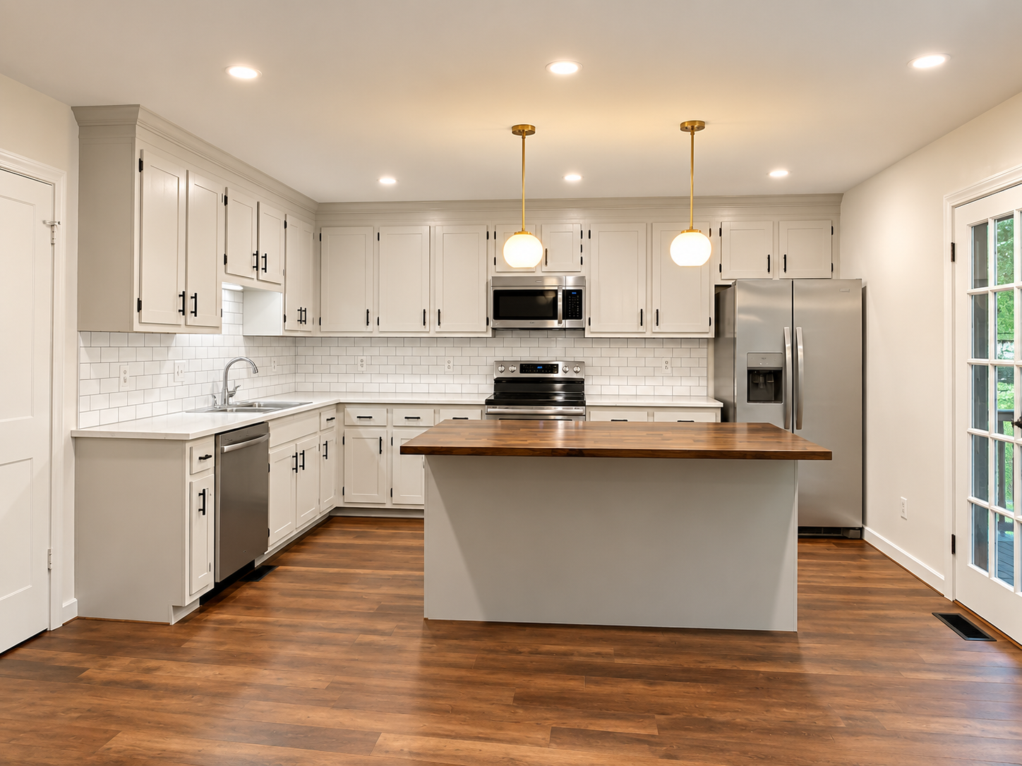 Modern kitchen with white cabinets, stainless steel appliances, a wooden island, white subway tile backsplash, hardwood floors, and large windows.