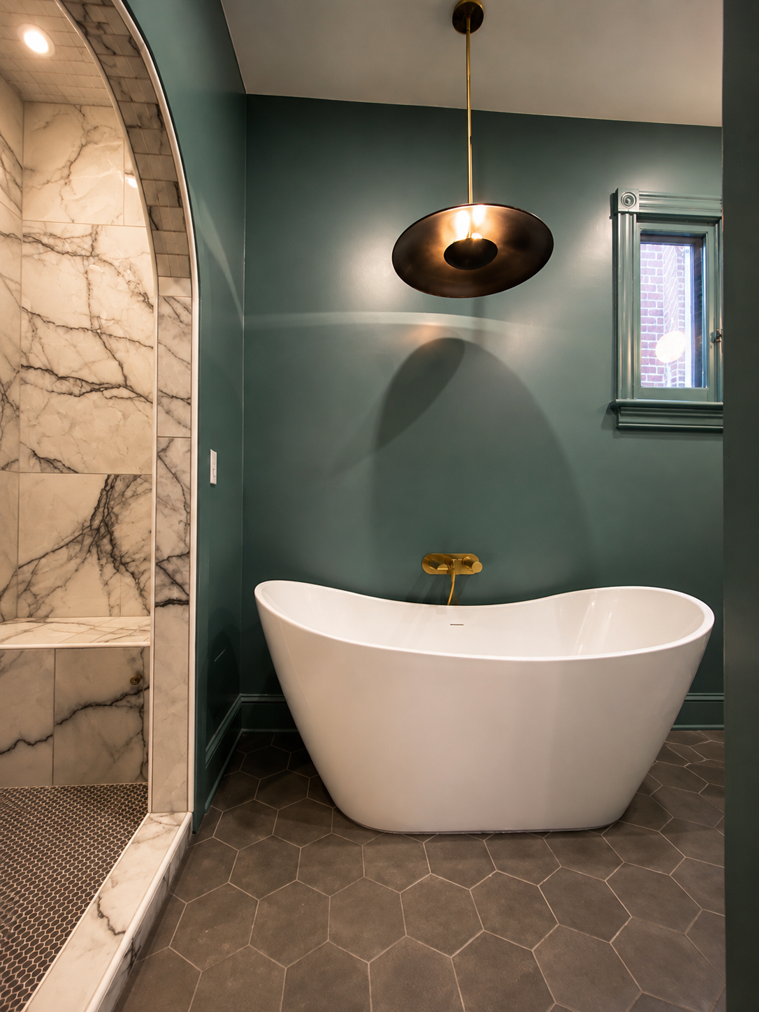 Modern bathroom with a white freestanding bathtub, a marble shower area, dark hexagon tile flooring, teal walls, a small window, and a black pendant light.