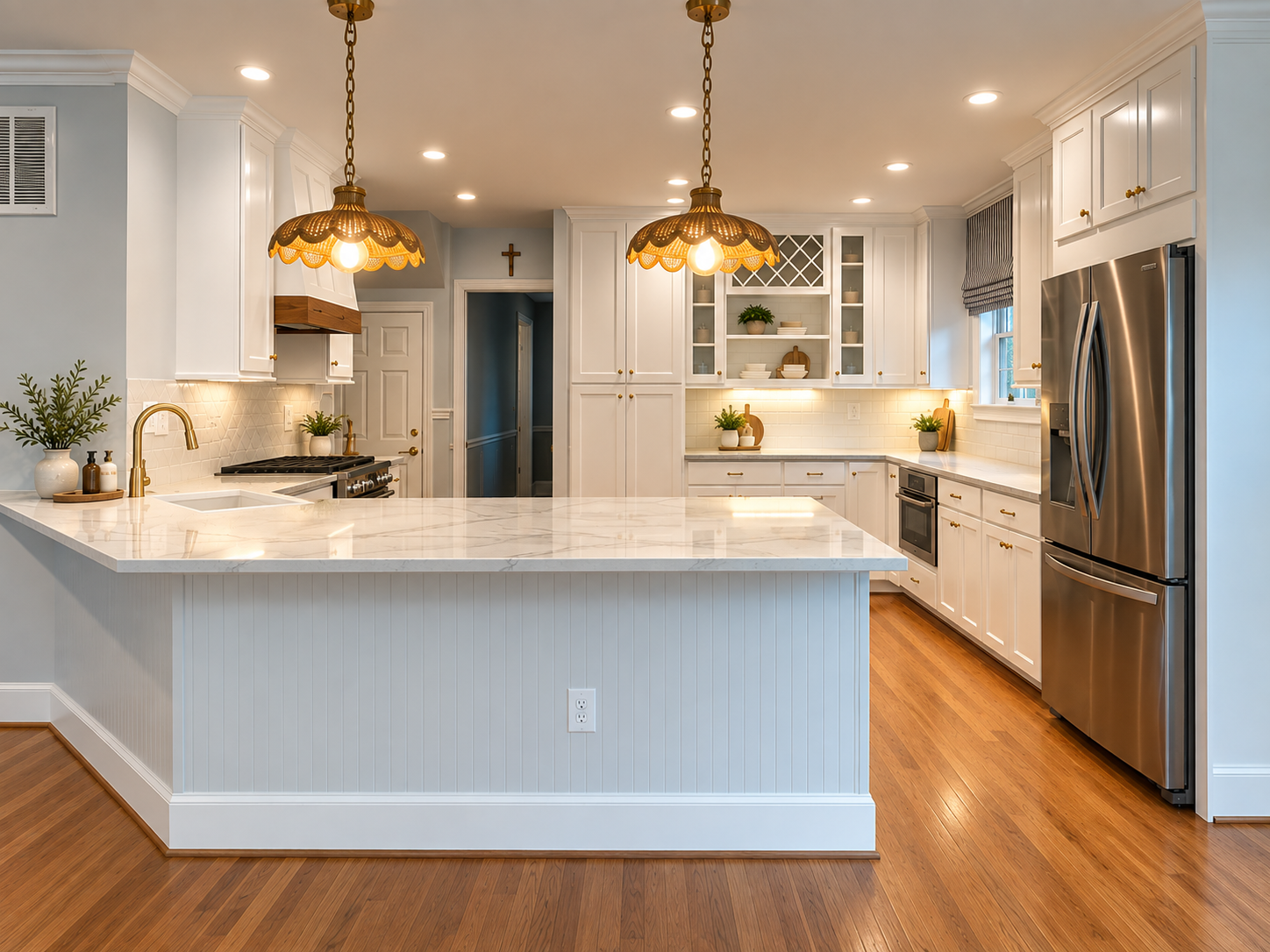 Modern kitchen with white cabinets, a marble island, wooden floors, stainless steel refrigerator, and warm lighting.