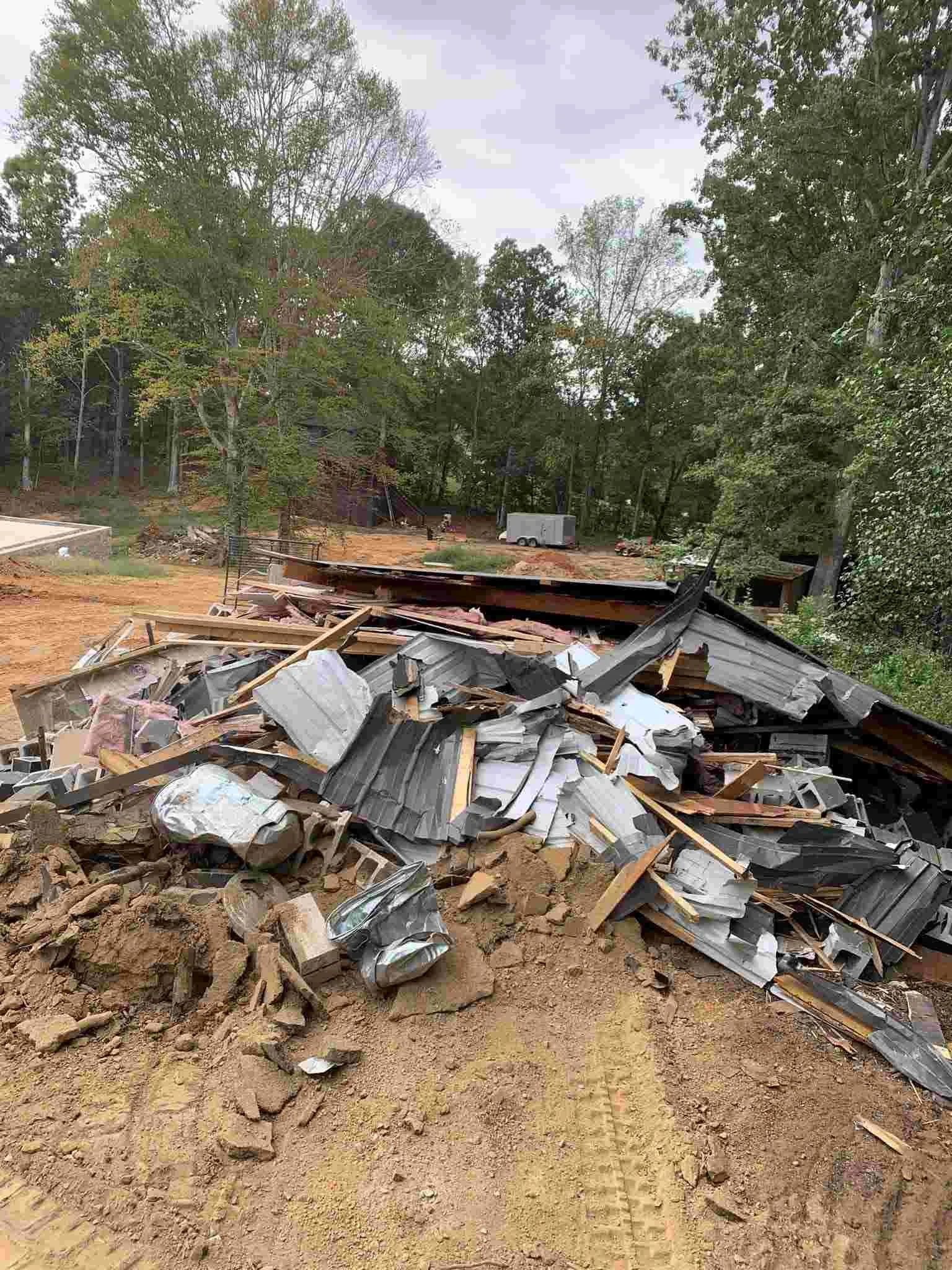 Demolished structure with metal roofing and wood debris on cleared land in McMinnville TN — W Services