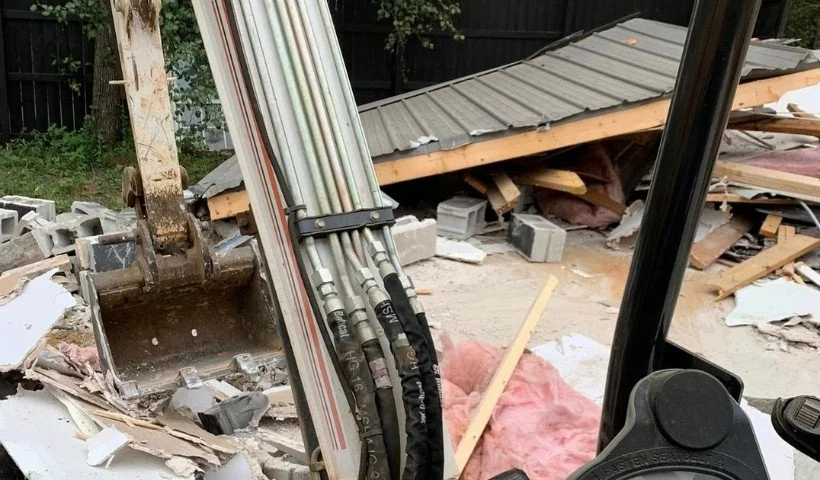 Mini excavator demolishing a small backyard structure