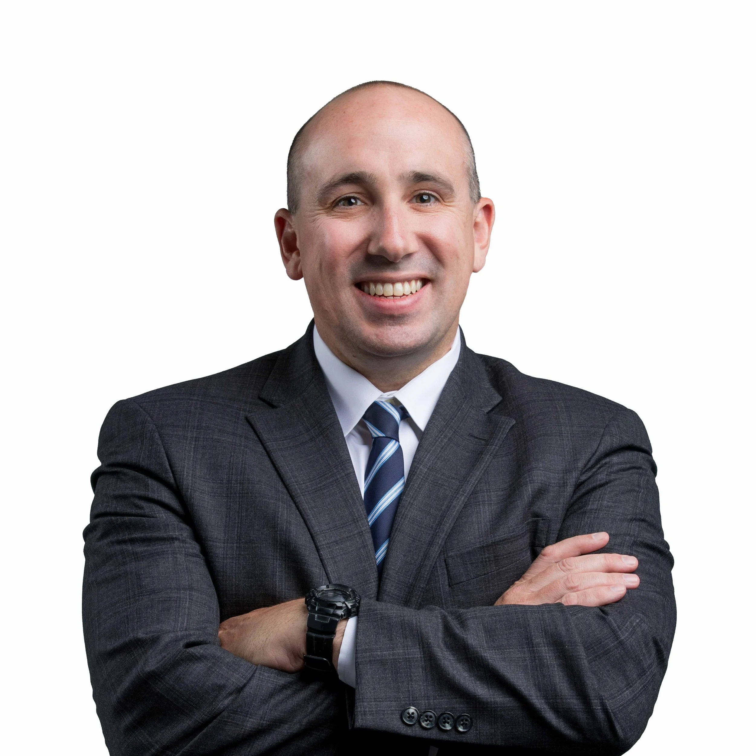 A professional man smiling with arms crossed, wearing a dark suit, white shirt, striped tie, and watch, against a white background.