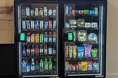 Two vending machines stocked with various snacks and beverages.