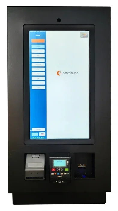 A digital kiosk with a large touchscreen displaying the Cantaloupe logo, a card reader, and a small printer at the bottom, used for self-service transactions.