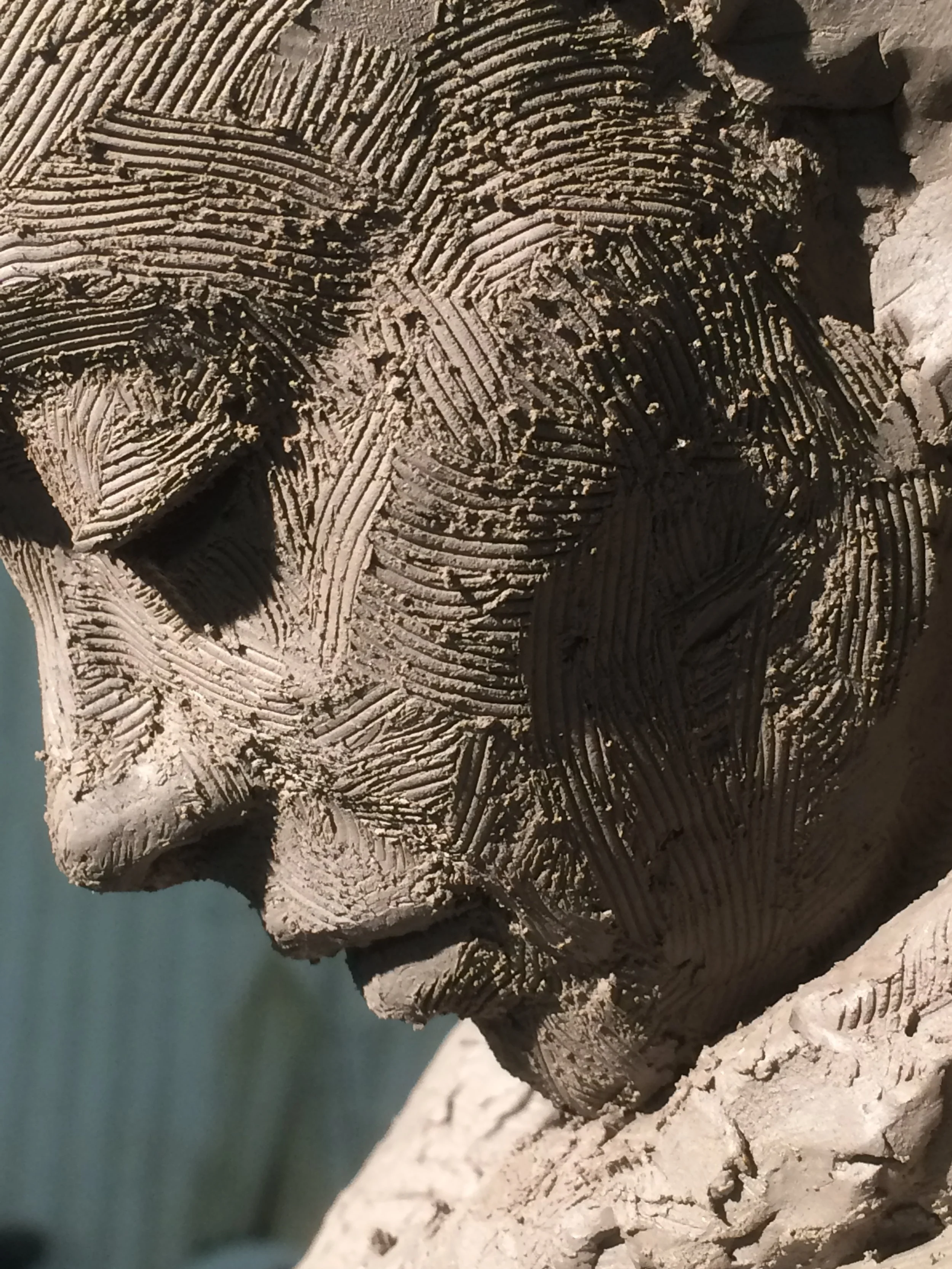 Close-up of a carved stone sculpture of a person's head, showing detailed textures and lines on the face.