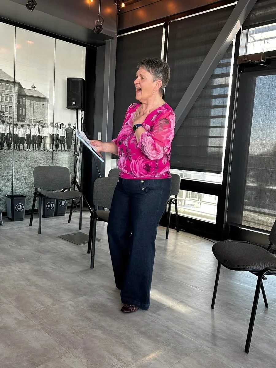 woman in her 60's wearing jeans and nice shirt speaking at an event.