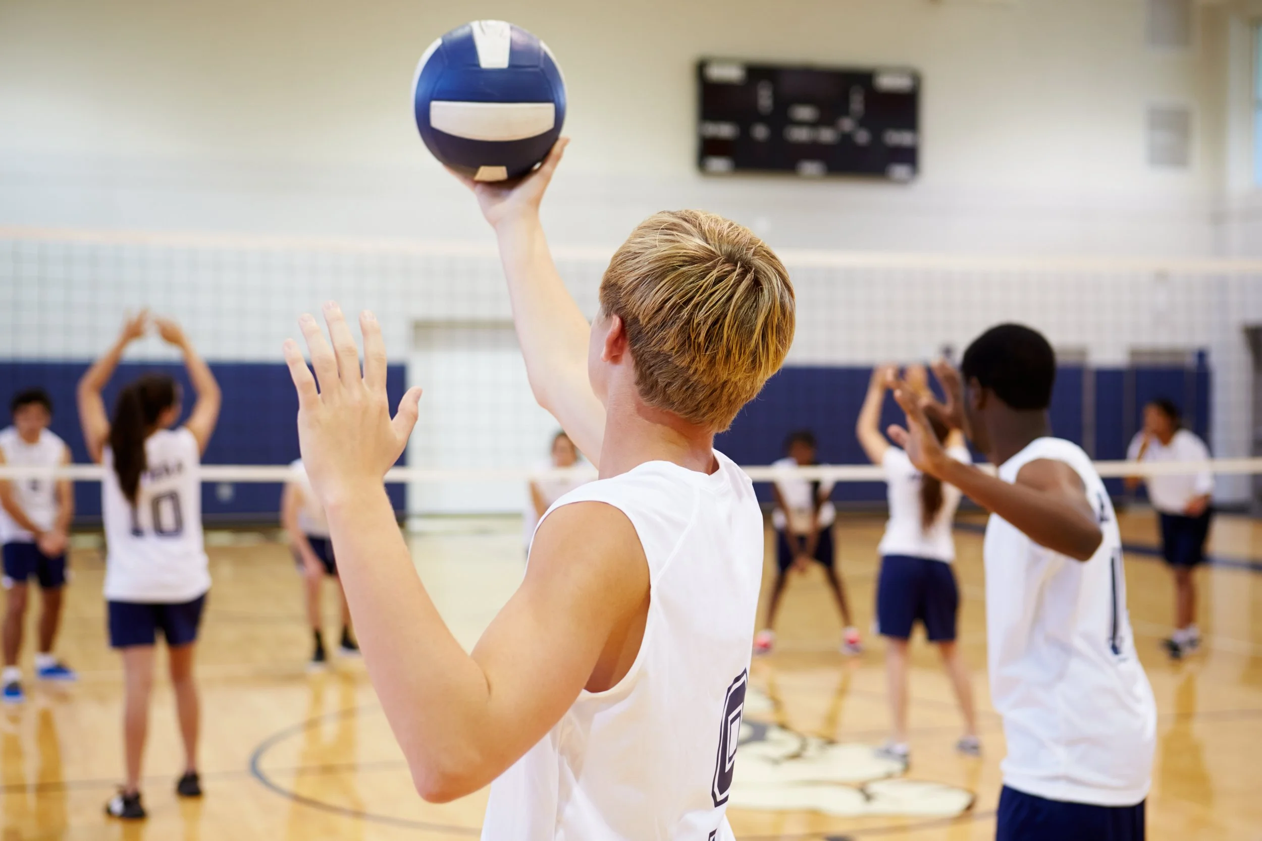 Boys playing volleyball in a gym