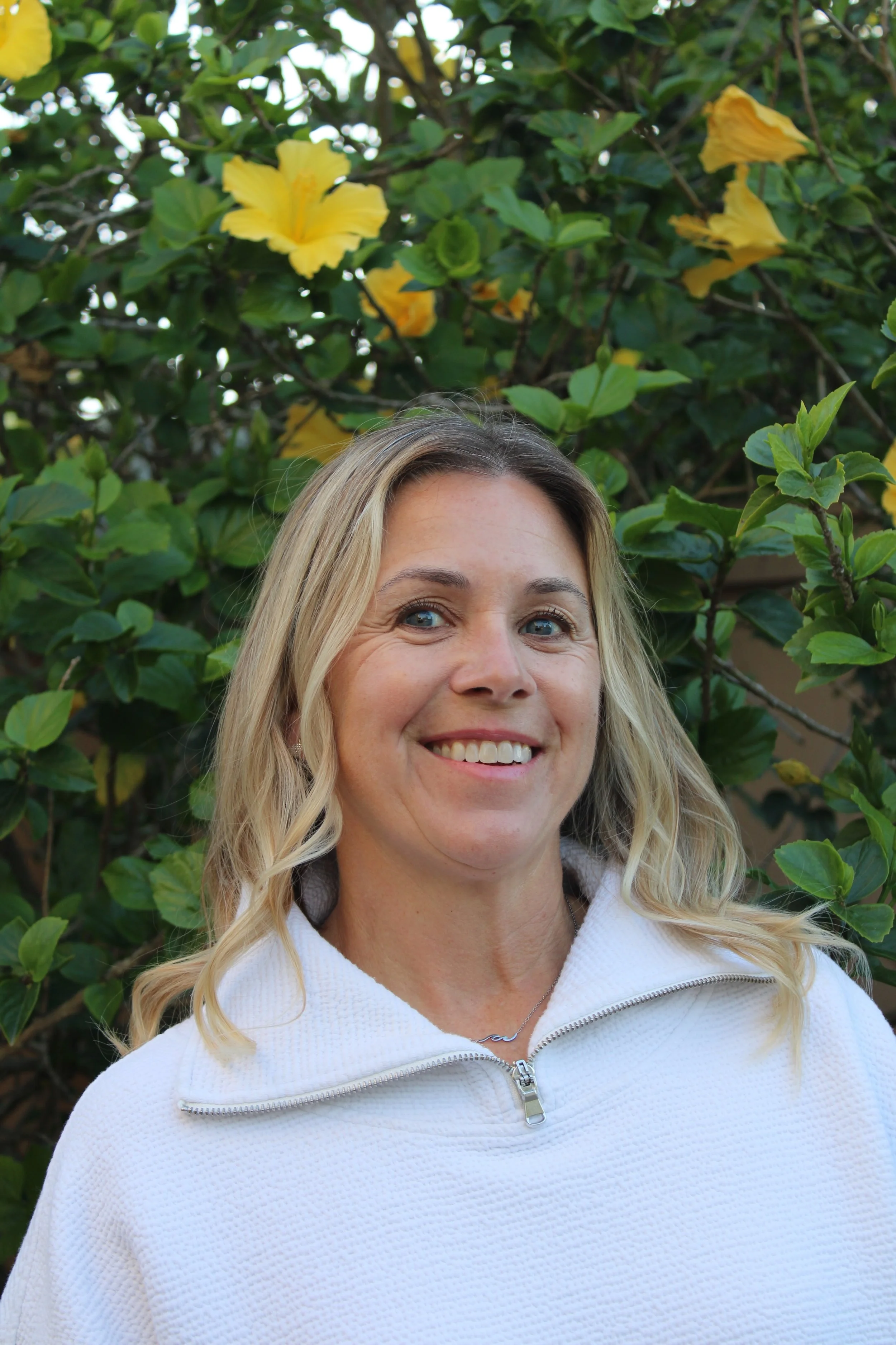 Kerry Stockel, founder, headshot outdoors with greenery behind her.