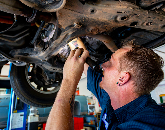 A mechanic inspecting the underside of a car in an auto repair shop Rochas Auto Service in Redding and Anderson, California