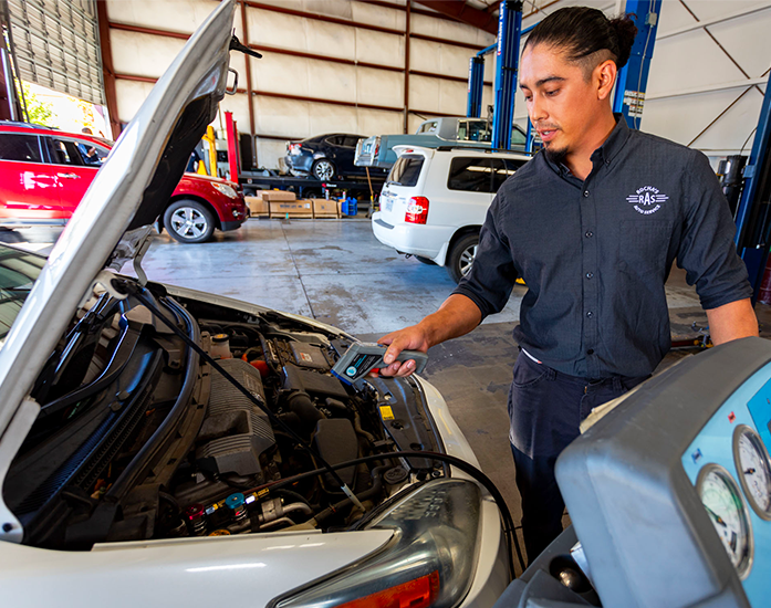 A mechanic inspecting a car engine in an auto repair shop Rochas Auto Service in Redding and Anderson, California