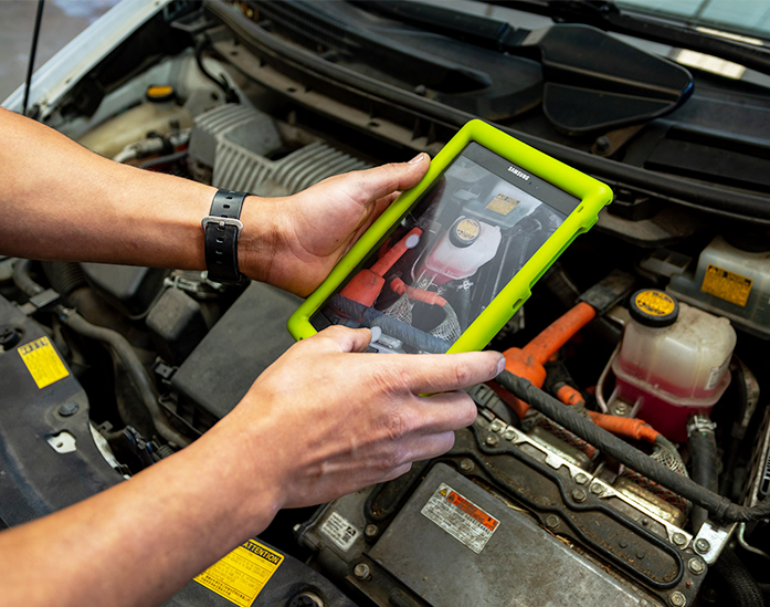 Mechanic using a tablet device to diagnose a car engine with an engine open Rochas Auto Service in Redding and Anderson, California