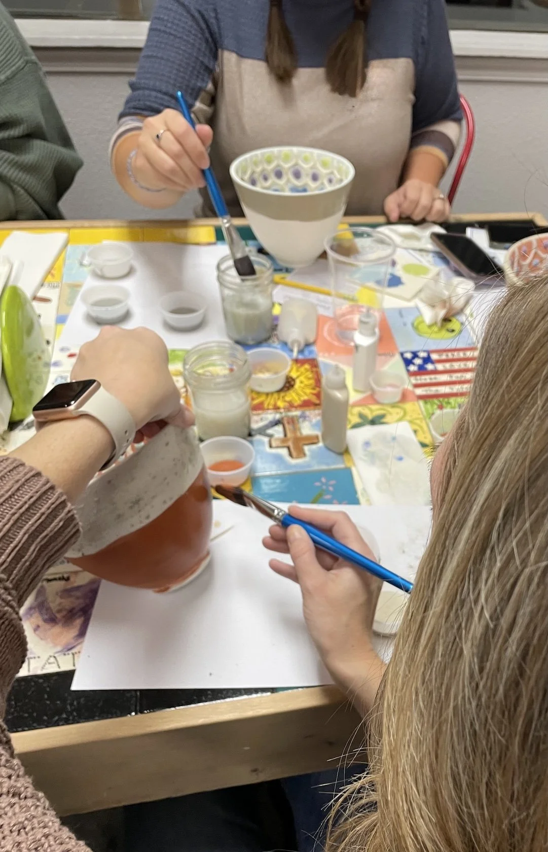 A woman paints a two-toned pottery piece