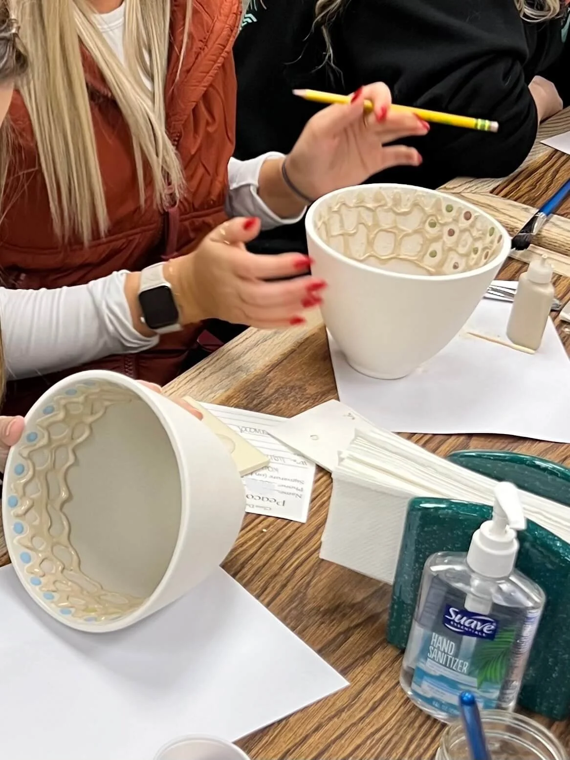 Two people paint the inside of their pottery bowls