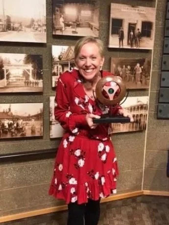 Kim sits on a pottery shelf