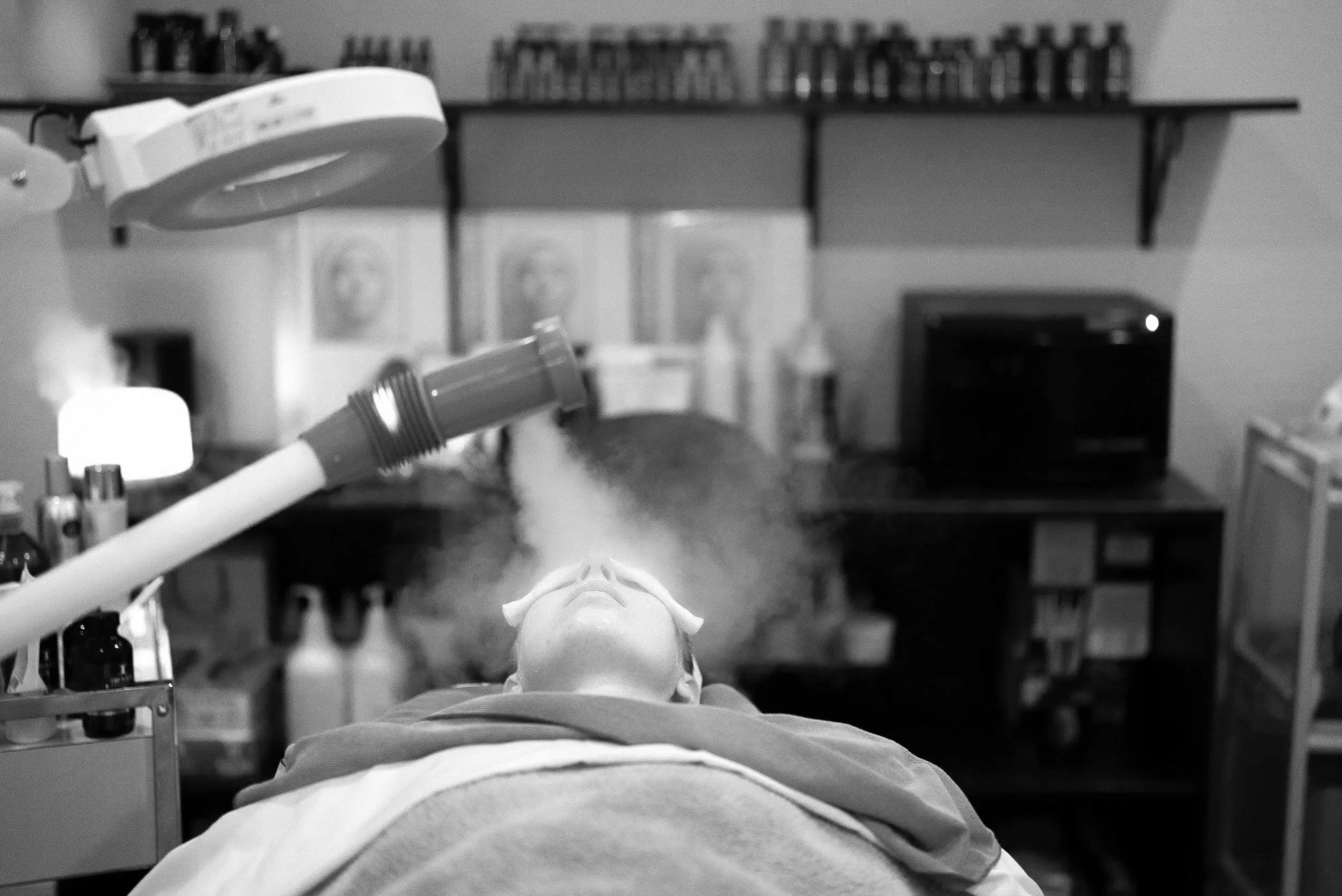 A person is receiving a facial treatment or skincare application in a spa or wellness setting, with the therapist or skincare specialist gently working on the client's face.