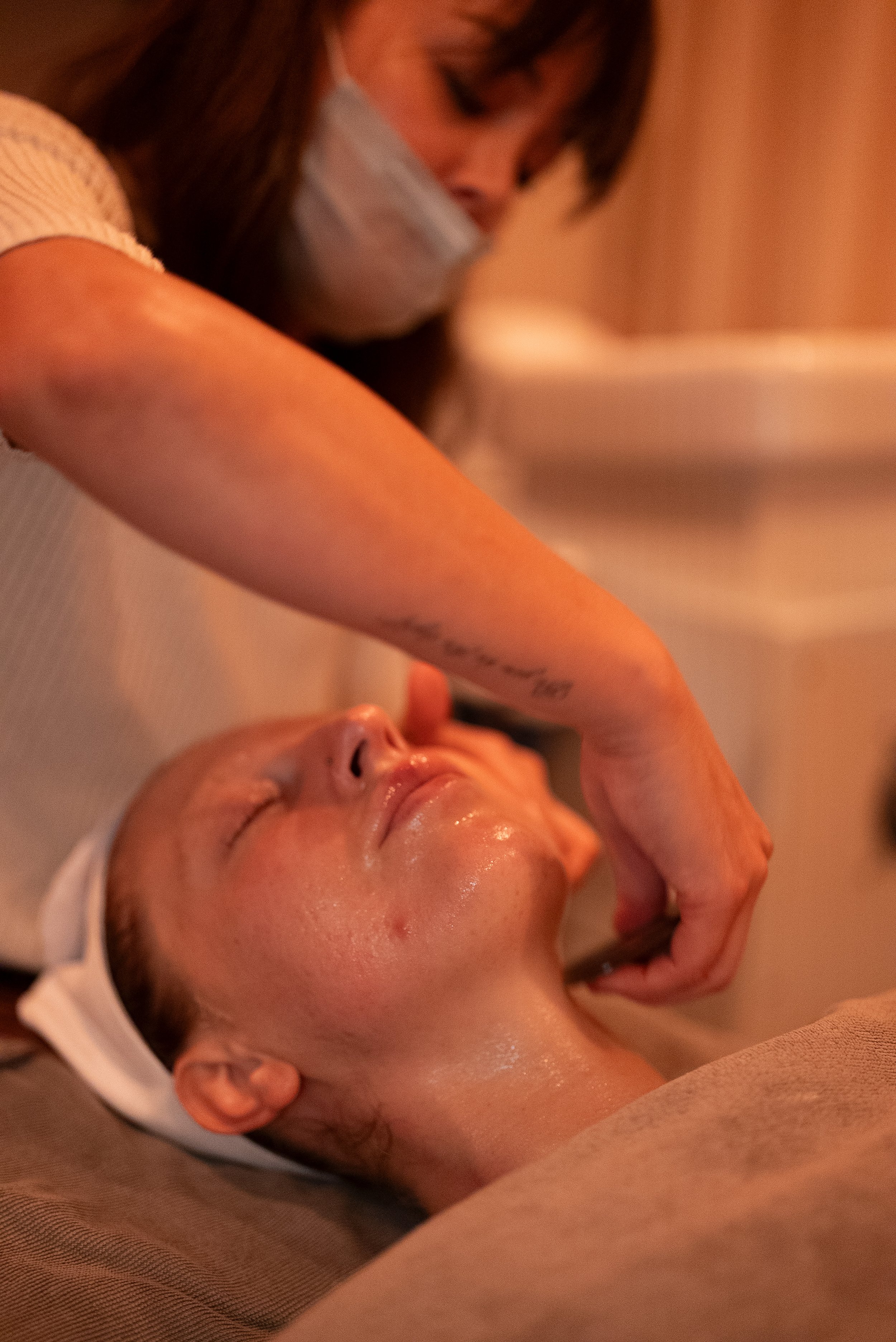 A woman receiving a facial treatment while lying down with her eyes closed.