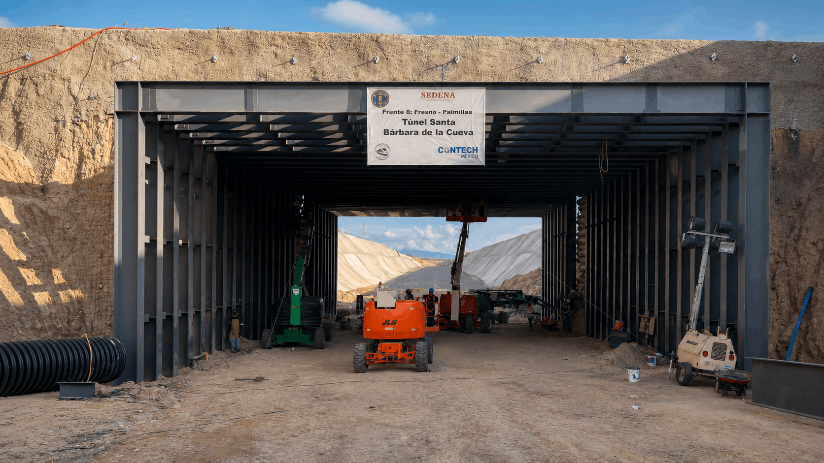 Obra en construcción de un túnel  inferior ferroviario llamado Túnel Santa Bárbara en un área de excavación con maquinaria y estructuras metálicas.