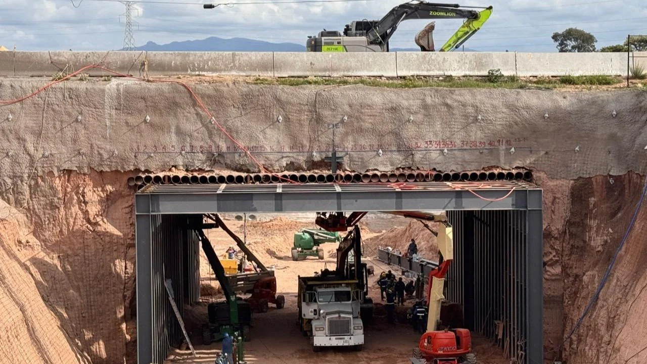 Construcción de un túnel inferio ferroviario con maquinaria y obreros en un sitio de obra.