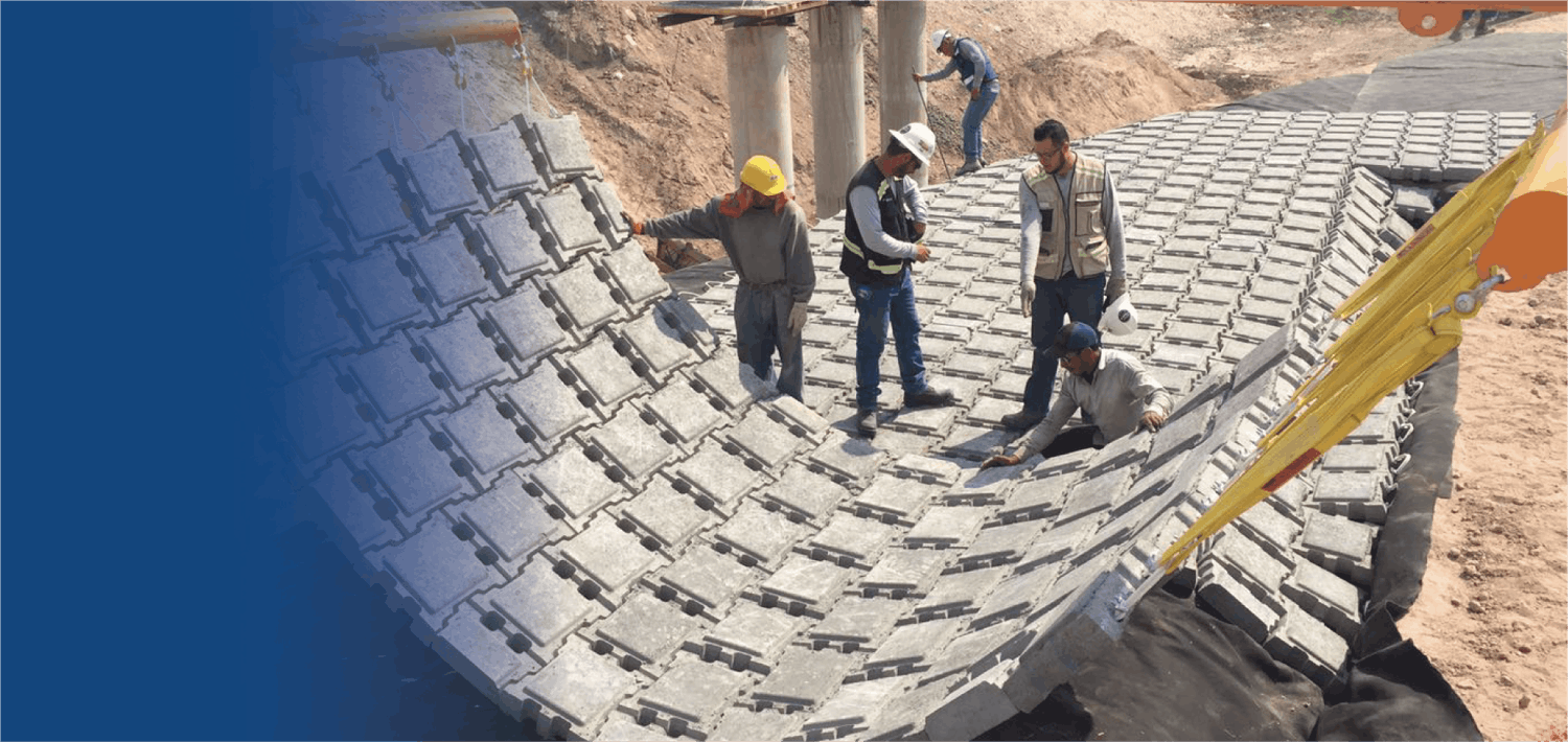 Trabajadores de construcción colocando Armorflex Tapered Block en un terreno para proteger ante desbordamiento de presas, aliviaderos y canales.