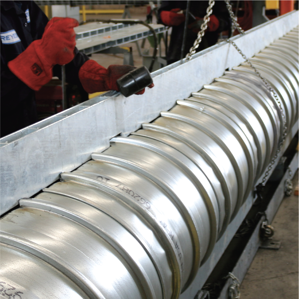 Trabajador con guantes rojos inspecciona componentes de una rueda de avión en una línea de ensamblaje industrial.