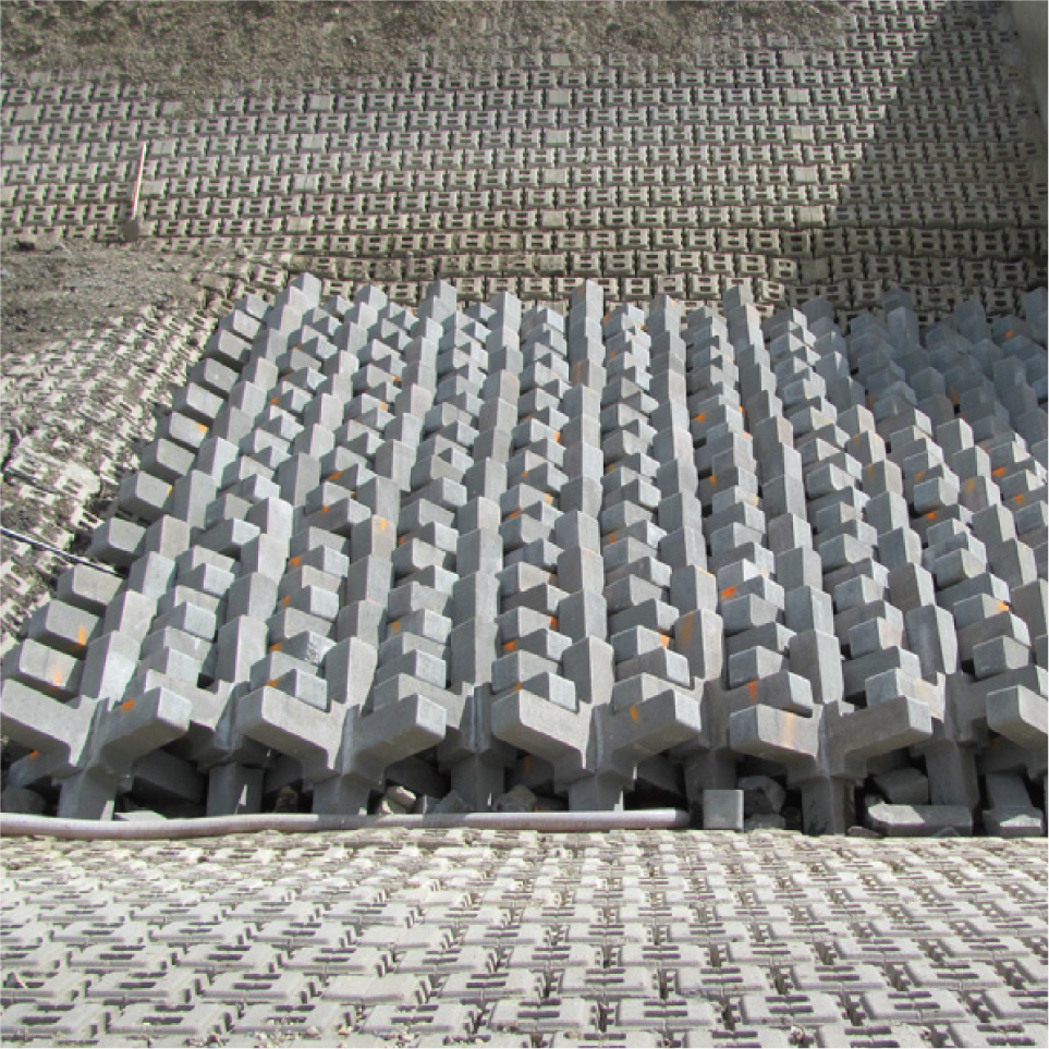 Escultura moderna formada por bloques de piedra gris con formas geométricas en diferentes alturas y ángulos, creando un patrón abstracto de líneas y volúmenes.