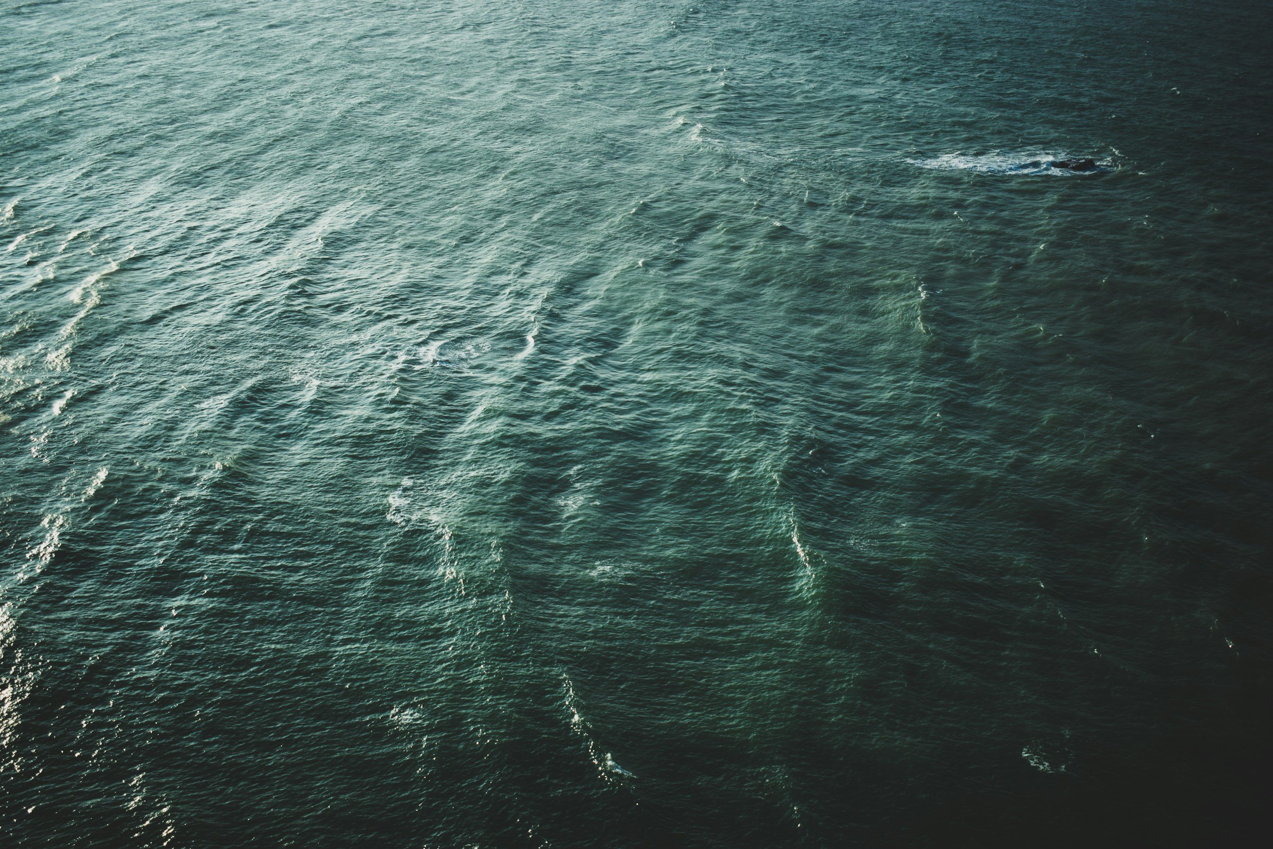 Aerial view of the ocean with visible wake patterns and gentle waves.