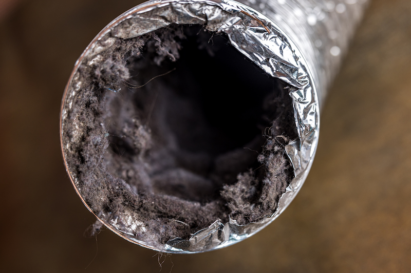 Close-up of a dusty, aluminum pipe with debris and dust inside.