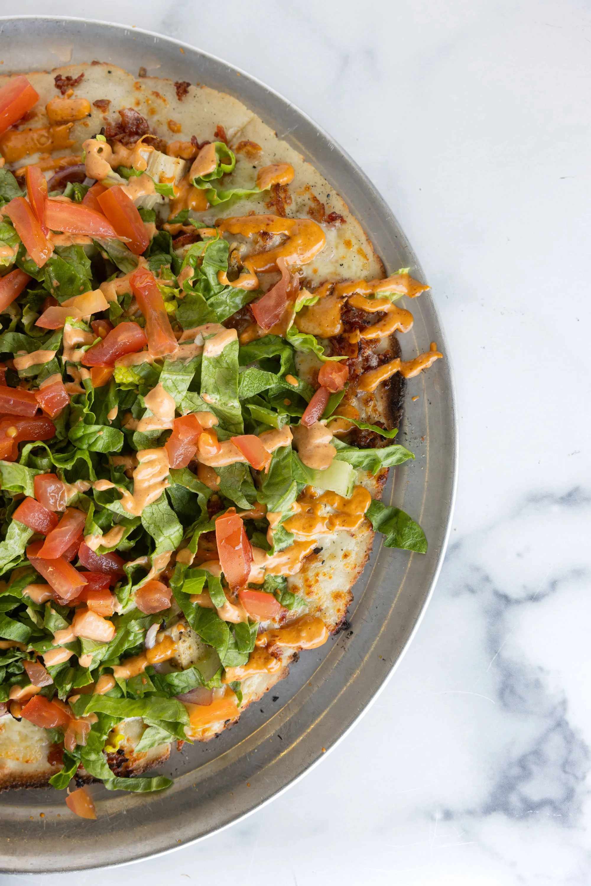 Gluten-free Southwest pizza topped with chicken, bacon, red onion, lettuce, tomato, and chipotle mayo.