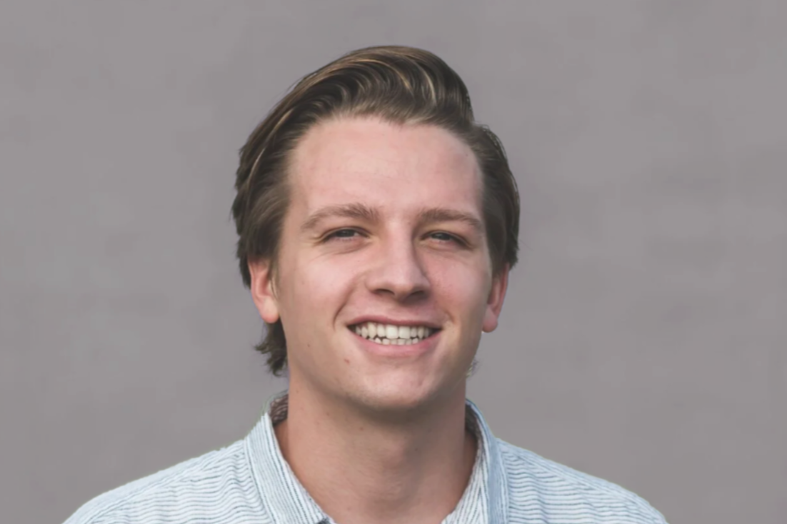 Tyler Ericson standing in front of a gray back drop.