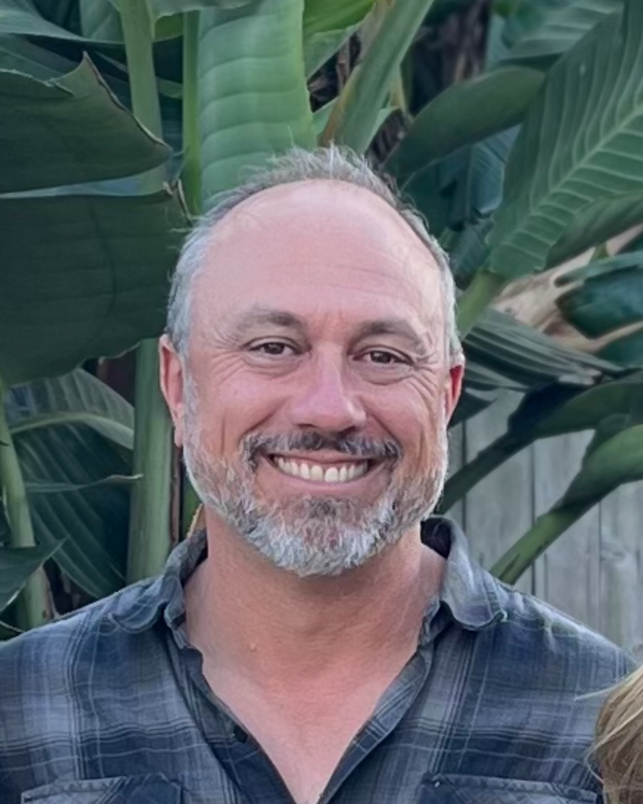 Dave Thibodeau standing in front of large leaves.