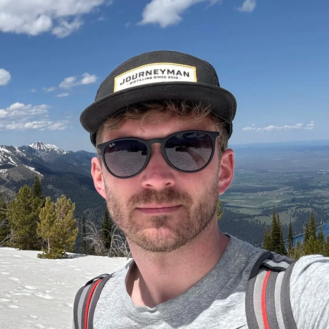 Travis Hagenbuch standing at the top of a mountain.